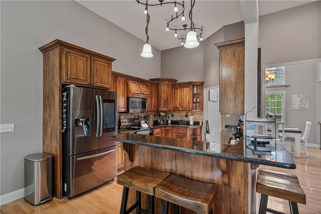 166 Woodford Way Southeast Calhoun, GA 30701 - Photo 15 of 44 a kitchen with stainless steel appliances granite countertop a refrigerator a stove a sink dishwasher a dining table and chairs with wooden floor