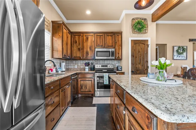 a kitchen with stainless steel appliances granite countertop a stove top oven a sink a dining table and chairs