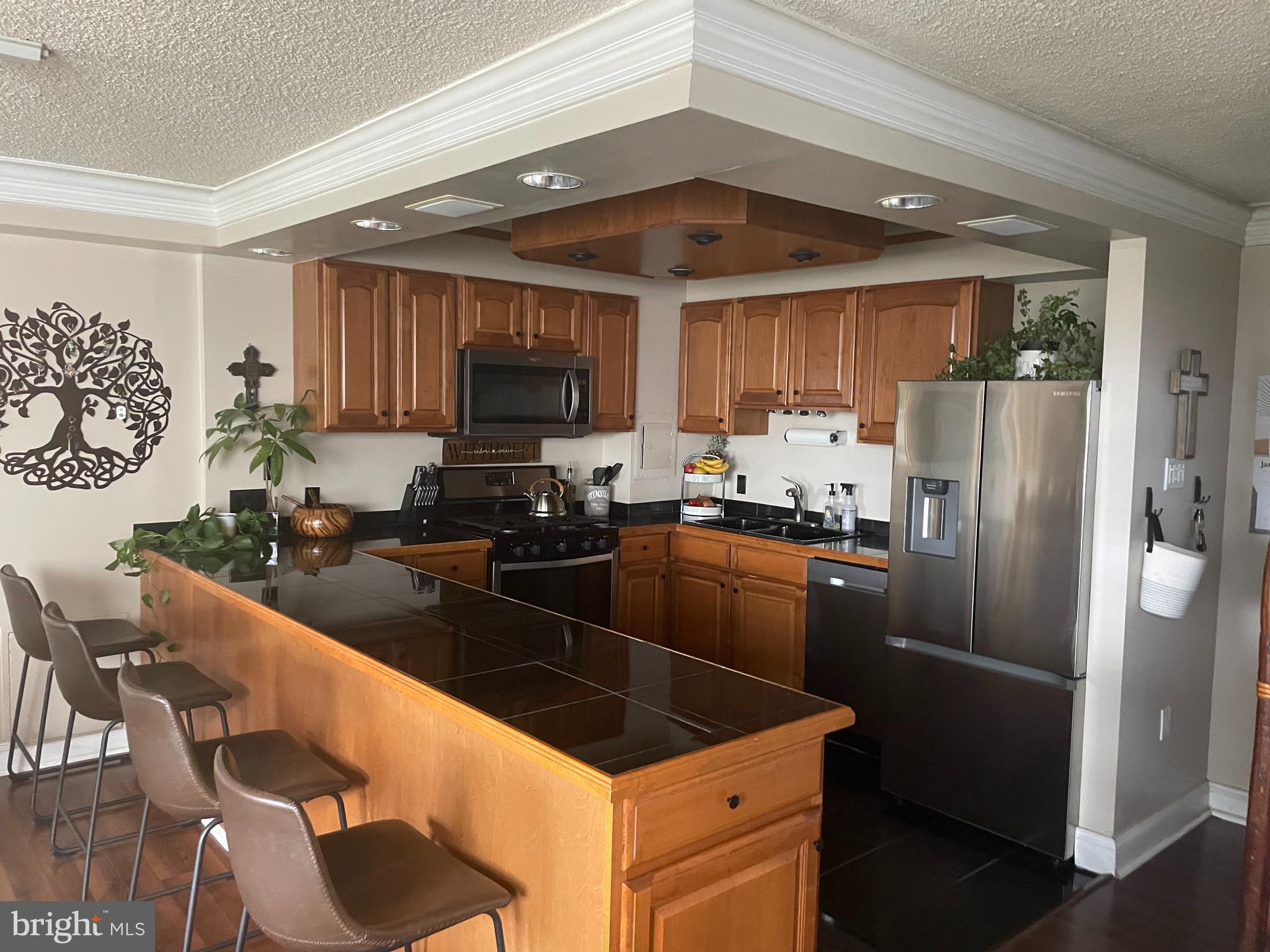 a kitchen with granite countertop a refrigerator a sink a stove a dining table and chairs