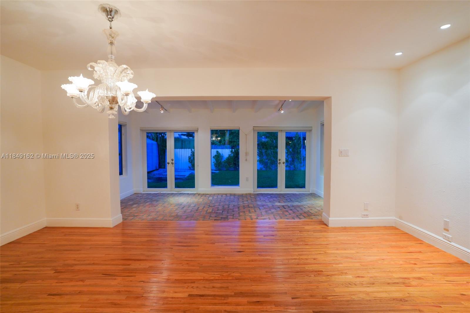 355 Redwood Lane Key Biscayne, FL 33149 - Photo 13 of 34 a view of an empty room with wooden floor and a chandelier