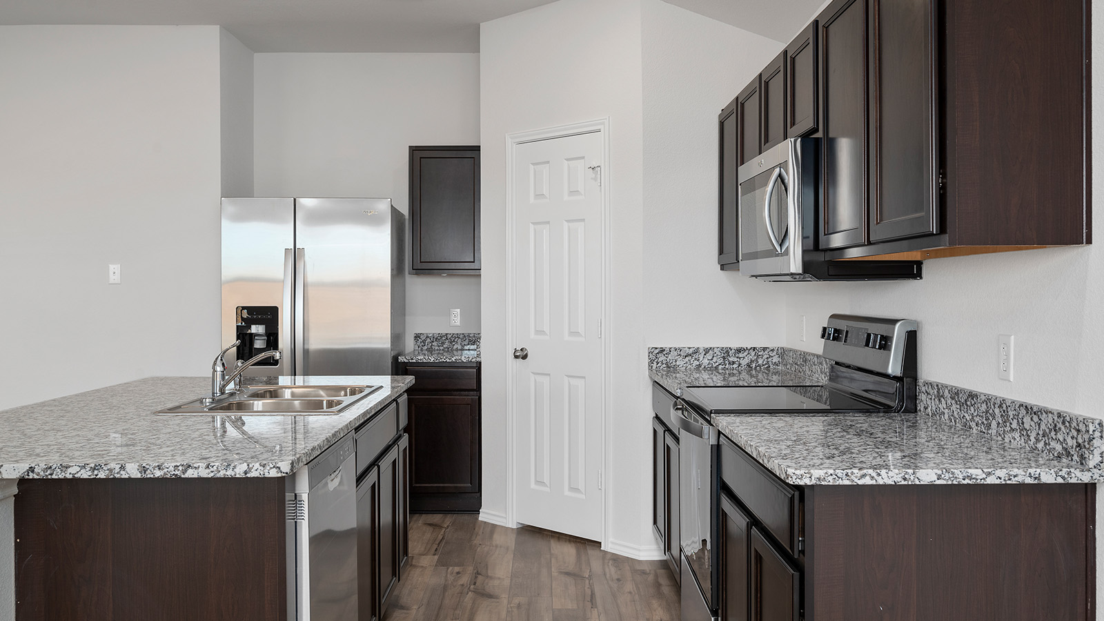 1403 Victory Rnch Trail Killeen, TX 76549 - Photo 4 of 22 The kitchen features dark wood cabinetry, light speckled countertops, and stainless steel appliances, including a microwave, range, and refrigerator