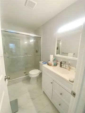 a bathroom with a granite countertop sink toilet a mirror and shower