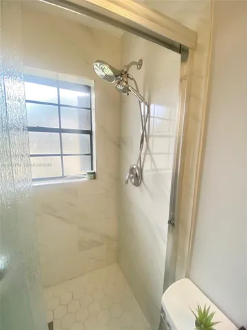 a bathroom with a granite countertop shower a toilet and a window