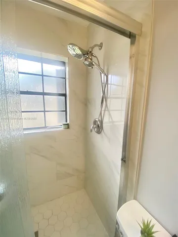 a bathroom with a granite countertop shower a toilet and a window