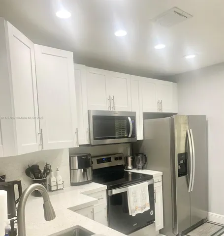 a kitchen with stainless steel appliances granite countertop a refrigerator a stove and a sink