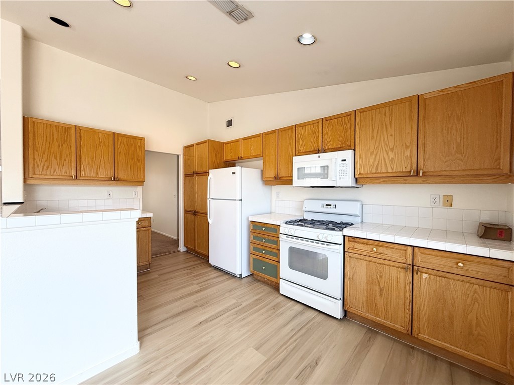 8870 Haviland Road Las Vegas, NV 89123 - Photo 7 of 24 Step into a well-lit kitchen featuring wood cabinetry and sleek appliances.