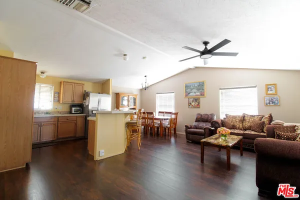 a living room with furniture kitchen view and a wooden floor