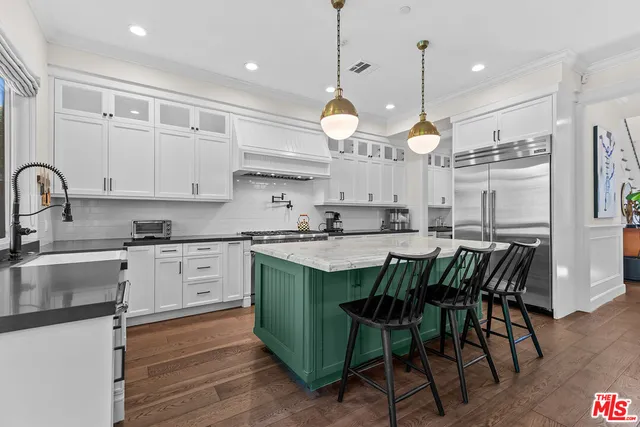 a large kitchen with granite countertop a stove a sink a center island and cabinets