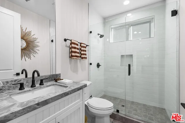 a bathroom with a granite countertop sink a toilet and shower