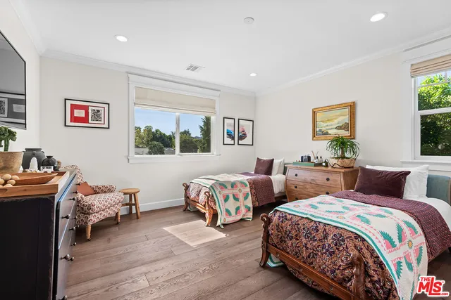 a bedroom with two beds and a dresser next to a window