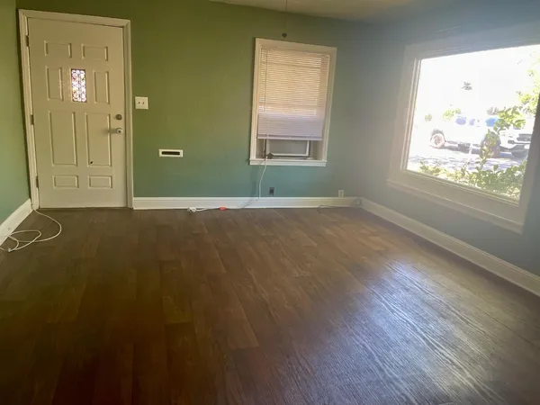 an empty room with wooden floor and windows