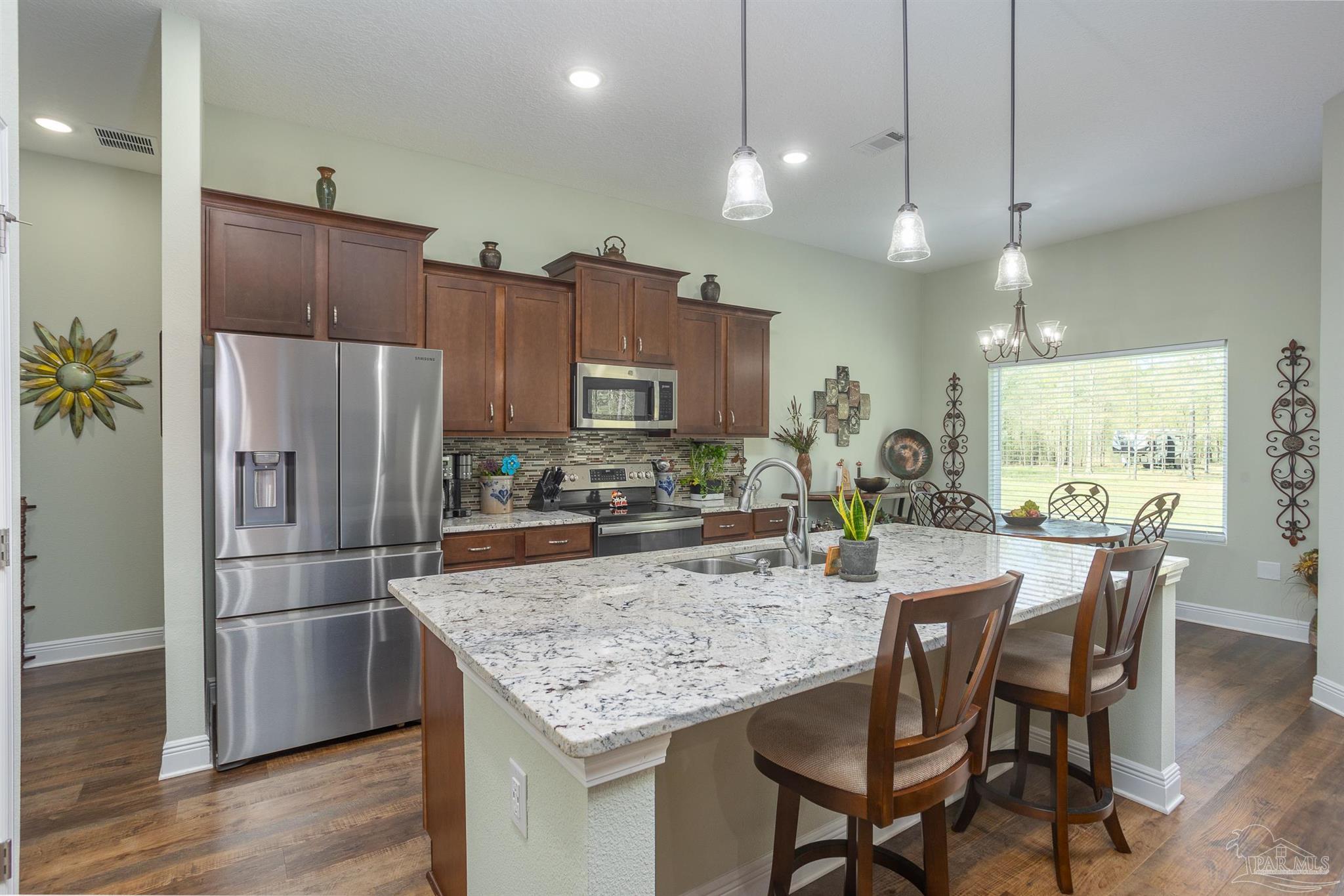 2383 Bud Diamond Road Jay, FL 32565 - Photo 6 of 50 a kitchen with stainless steel appliances a dining table chairs refrigerator and microwave