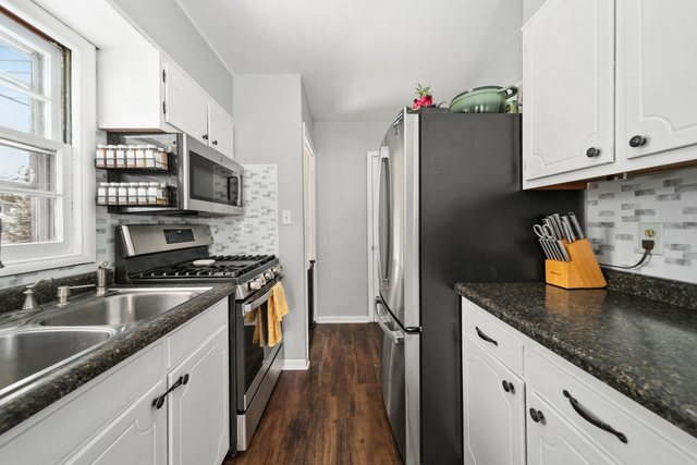 228 West Taylor Street DeKalb, IL 60115 - Photo 11 of 30 a kitchen with stainless steel appliances granite countertop a sink stove and refrigerator