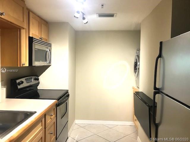 2630 Southwest 28th Street, Unit 26 Miami, FL 33133 - Photo 3 of 6 a kitchen with stainless steel appliances granite countertop a refrigerator a stove and a sink with wooden floor