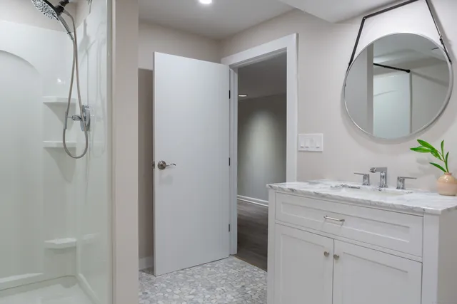 a bathroom with a granite countertop sink a mirror and a shower