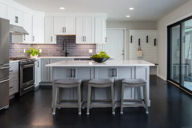 a kitchen with stainless steel appliances a table chairs refrigerator and microwave