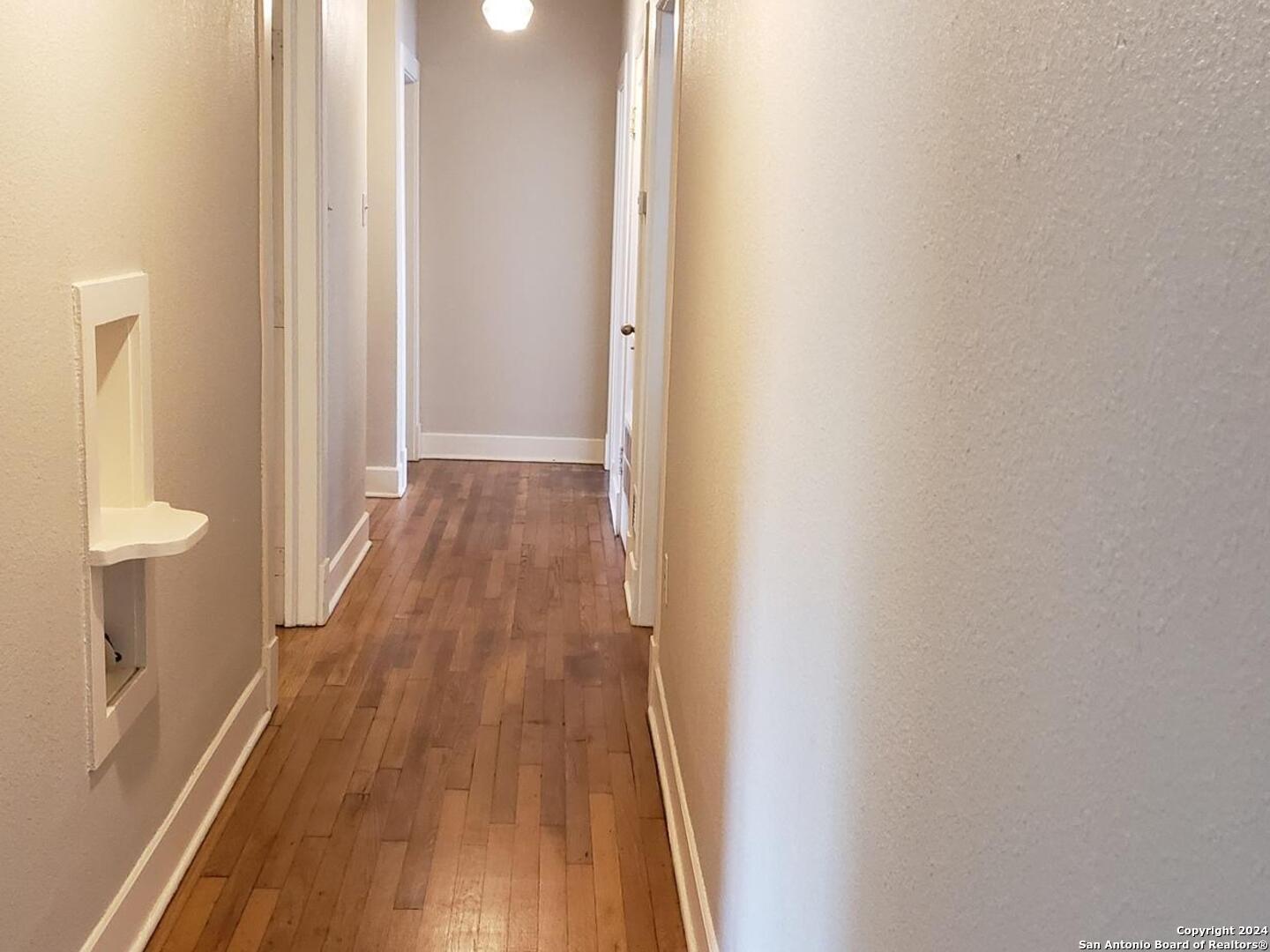 1406 Hicks Avenue San Antonio, TX 78210 - Photo 5 of 14 a view of a hallway with wooden floor and a bathroom