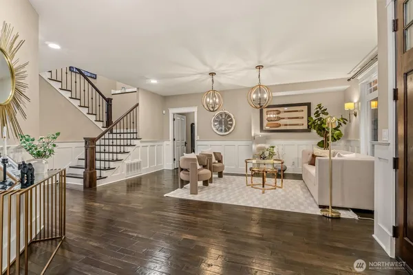 a living room with couches and kitchen view with wooden floor