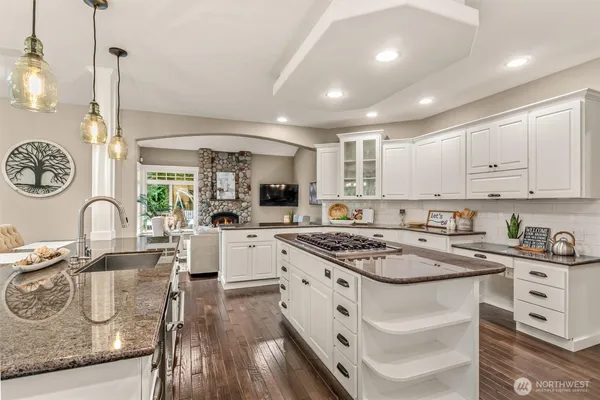 a kitchen with kitchen island granite countertop a sink a stove cabinets and wooden floor