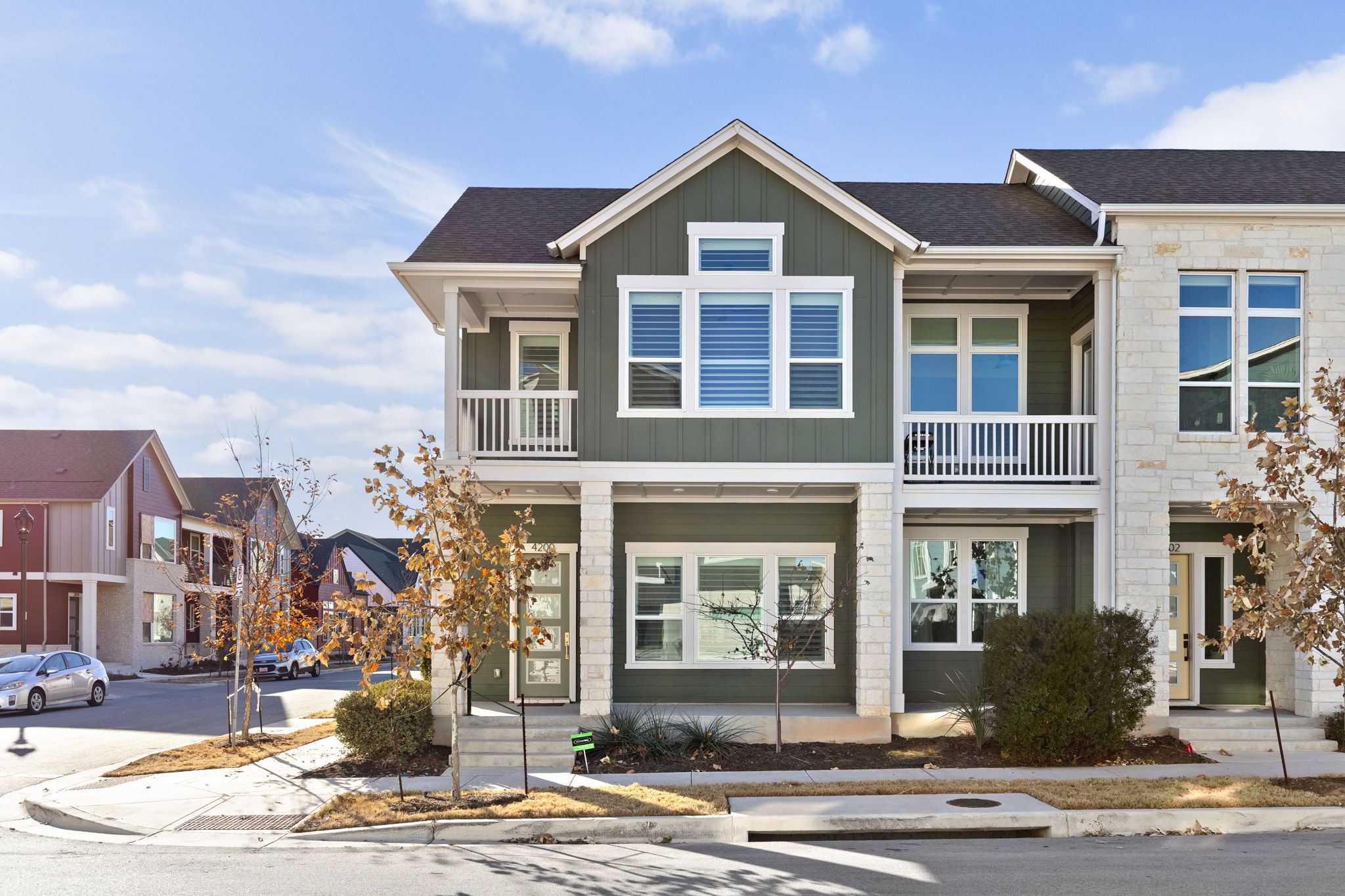 View of front of property with board and batten siding, a balcony, a residential view, and roof with shingles