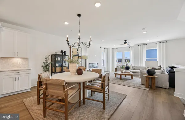 a view of a dining room and livingroom with furniture wooden floor a rug a flat screen tv a painting and a chandelier