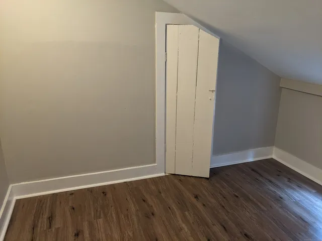 a view of an empty room with wooden floor and closet