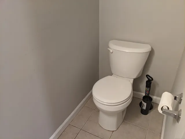 a white toilet sitting next to a white wall