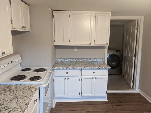 a kitchen with granite countertop a sink a stove and cabinets