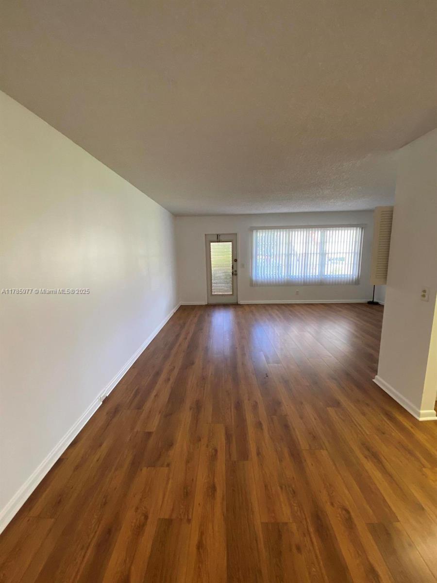 381 Fanshaw J, Unit 381 Boca Raton, FL 33434 - Photo 2 of 13 a view of empty room with window and wooden floor