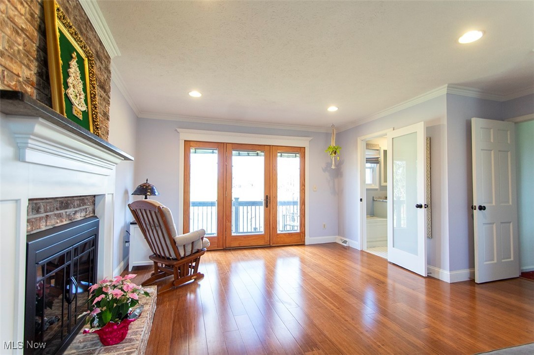 4041 Huffman Road Medina, OH 44256 - Photo 19 of 40 Living area featuring french doors, hardwood / wood-style flooring, a brick fireplace, and crown molding