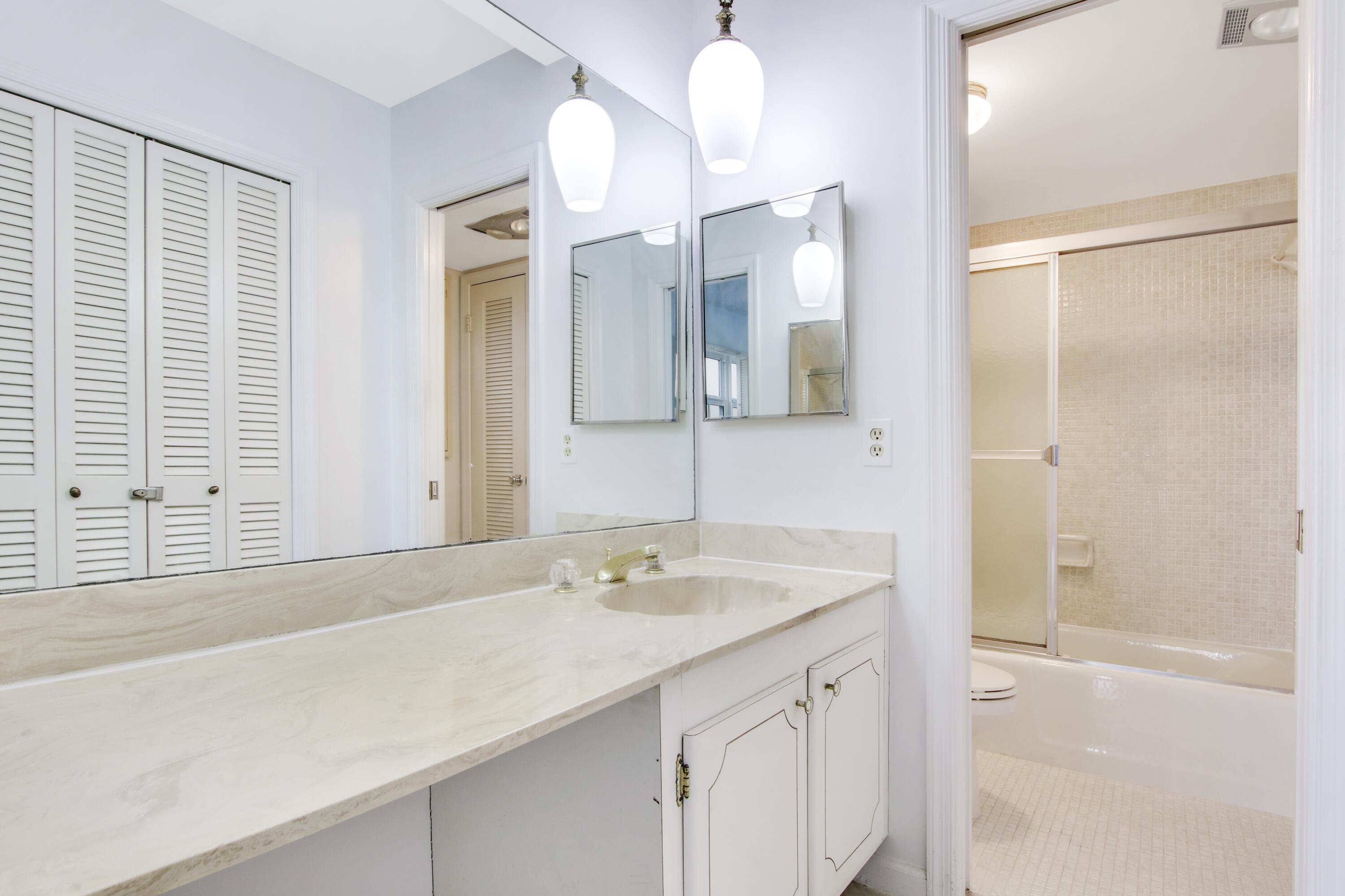145 Atlantis Boulevard, Unit 105 Atlantis, FL 33462 - Photo 28 of 28 a bathroom with a shower sink and mirror