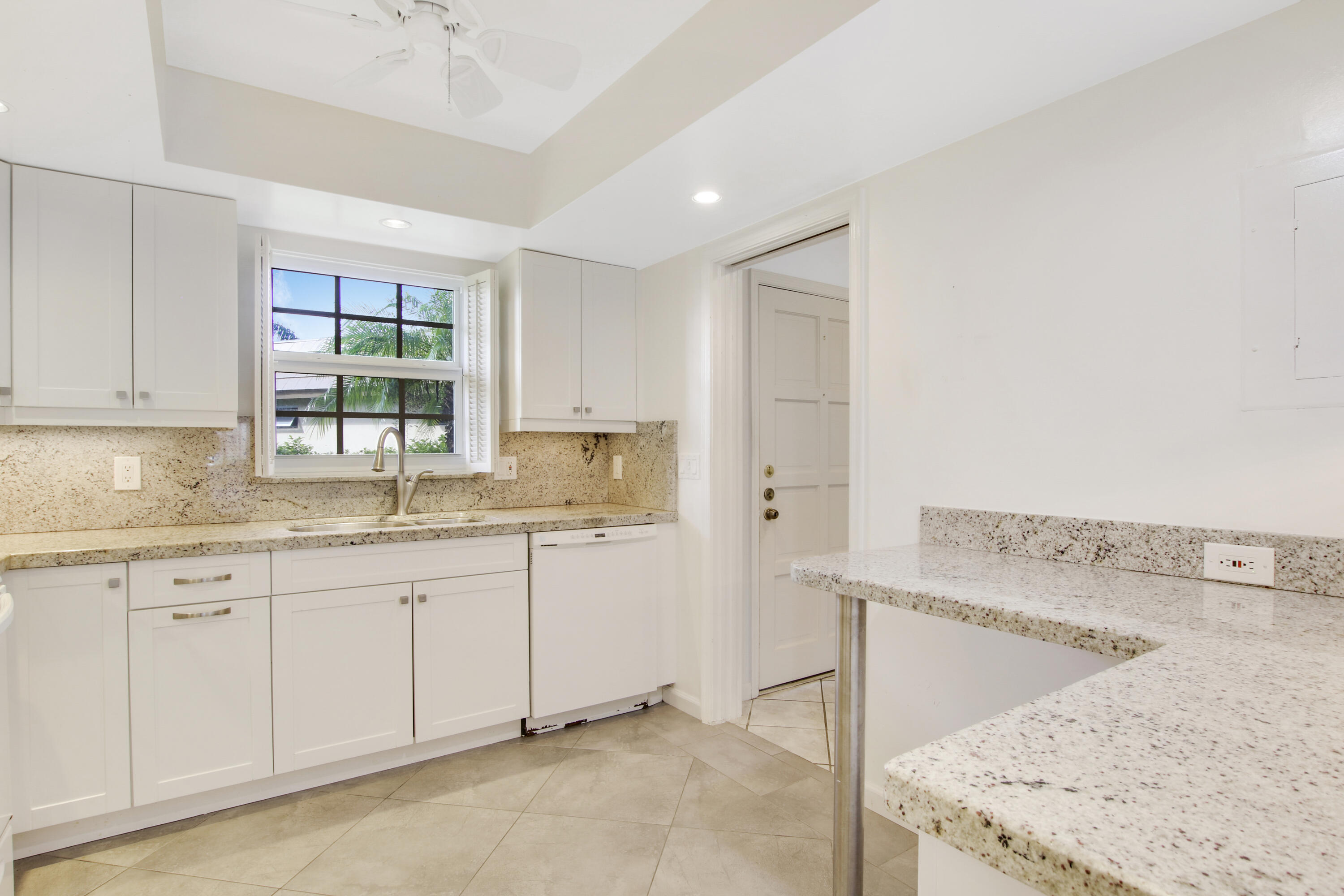 145 Atlantis Boulevard, Unit 105 Atlantis, FL 33462 - Photo 7 of 28 a kitchen with granite countertop a sink and white cabinets