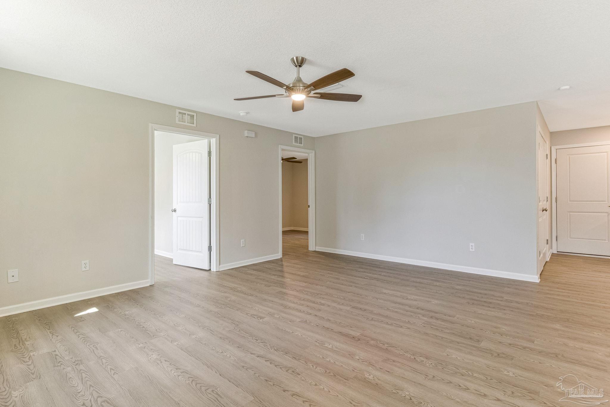 3152 Clemson Road Gulf Breeze, FL 32563 - Photo 15 of 56 a view of an empty room with wooden floor and a ceiling fan