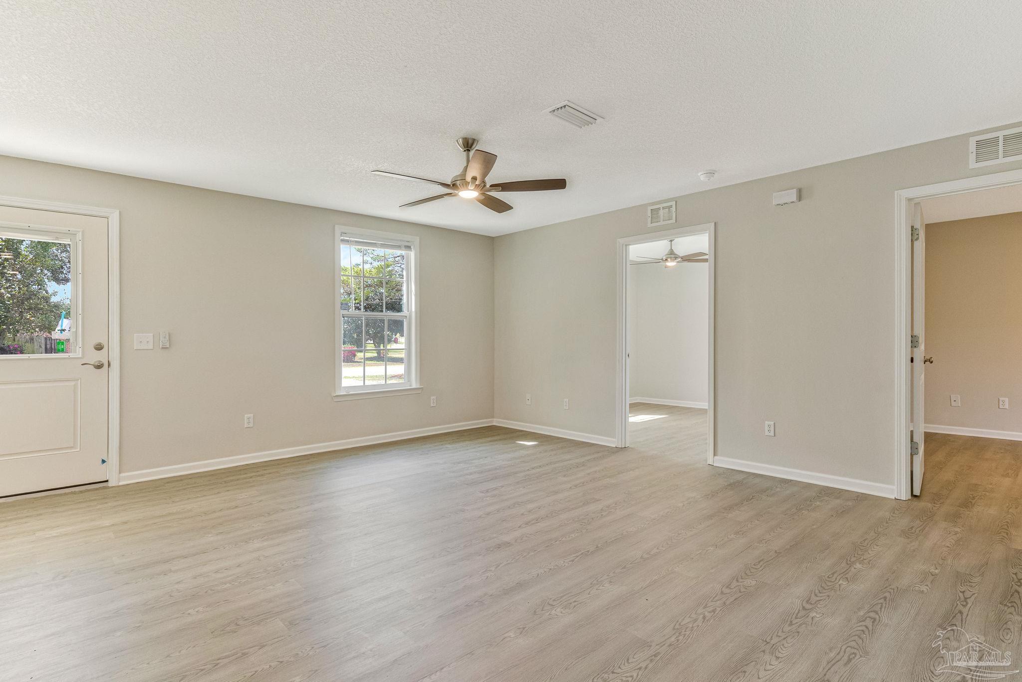 3152 Clemson Road Gulf Breeze, FL 32563 - Photo 16 of 56 an empty room with wooden floor ceiling fan and windows