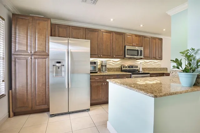a kitchen with stainless steel appliances granite countertop a refrigerator a stove and a sink with wooden cabinets