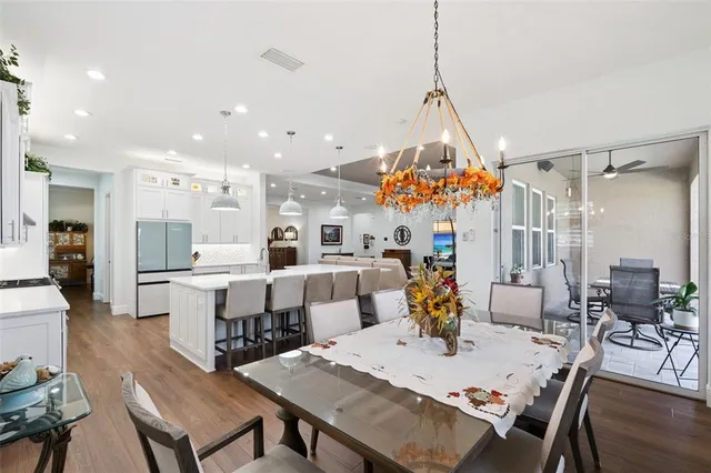 a large white kitchen with lots of counter space a sink appliances and dining table