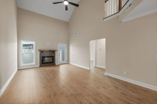 an empty room with wooden floor fireplace and windows