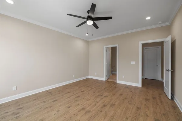 a view of empty room with wooden floor and ceiling fan