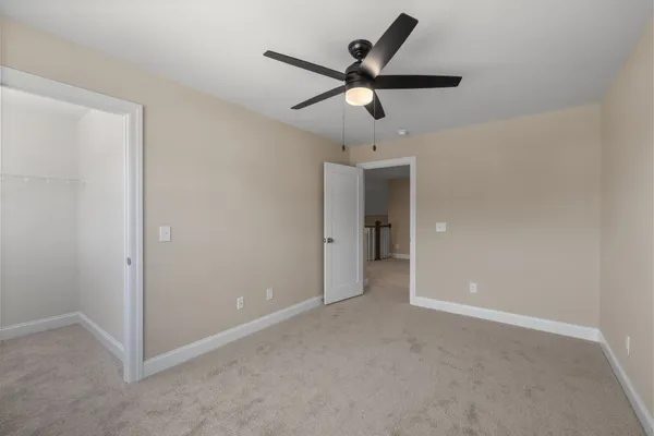an empty room and chandelier fan in hallway