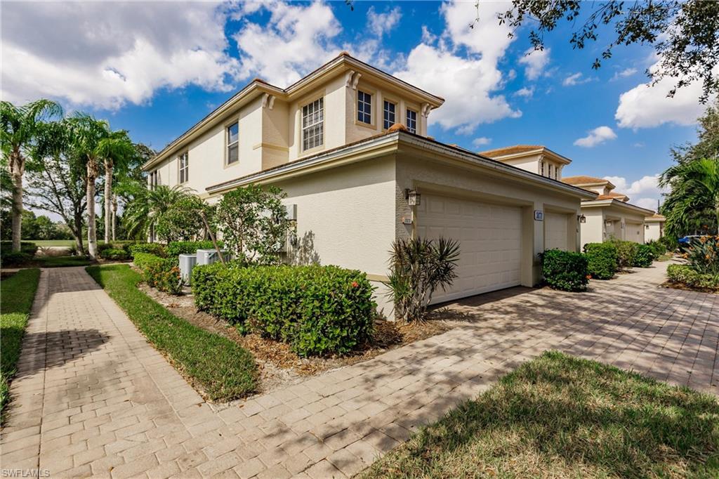 3071 Meandering Way, Unit 101 Fort Myers, FL 33905 - Photo 2 of 49 a front view of a house with a yard and garage