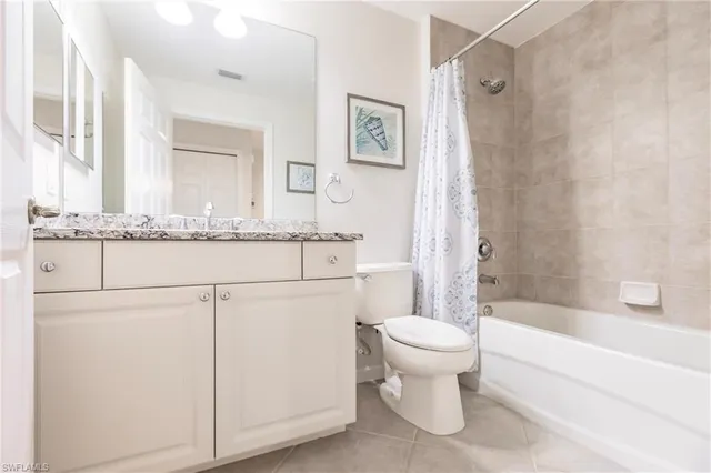 a bathroom with a granite countertop toilet sink and mirror