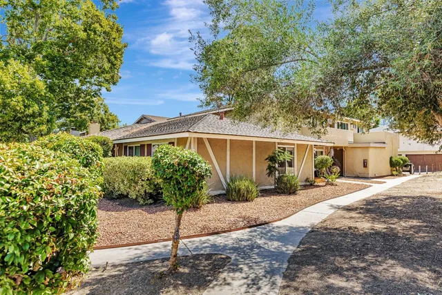 a front view of a house with a yard and potted plants