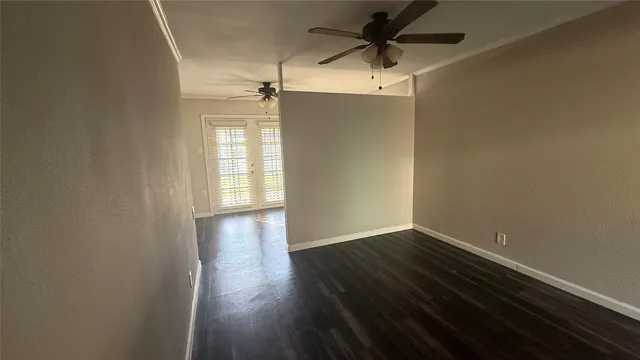 an empty room with wooden floor fan and windows