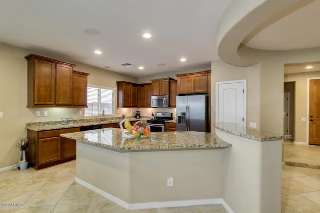 a large kitchen with granite countertop a large counter top stainless steel appliances and cabinets