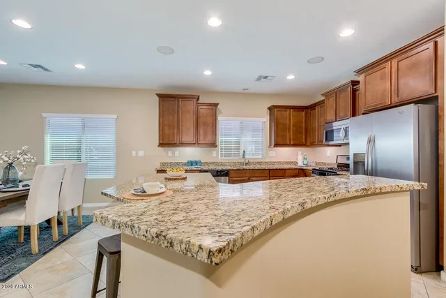 a large kitchen with kitchen island a large counter top stainless steel appliances and cabinets