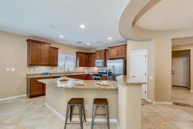 a kitchen with kitchen island a stove a sink a refrigerator and cabinets
