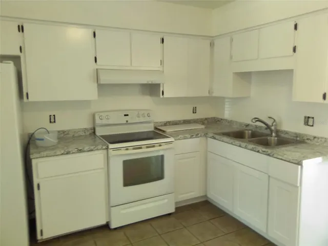 a kitchen with granite countertop white cabinets and white appliances