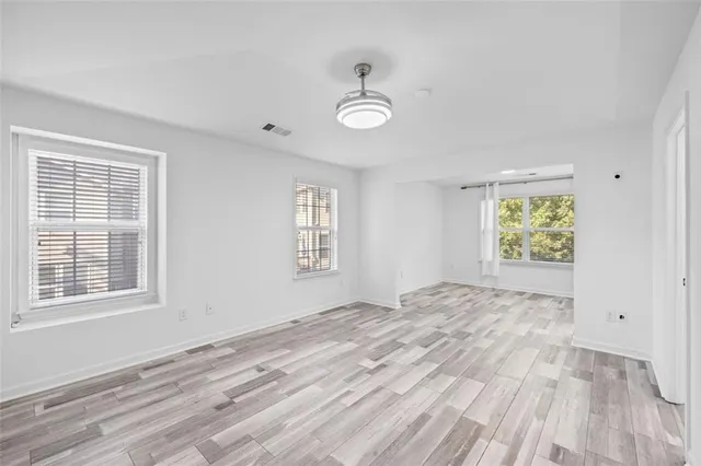 a view of empty room with wooden floor and window