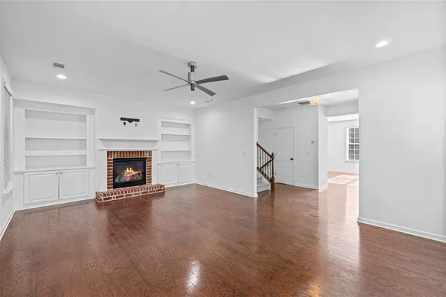 an empty room with wooden floor fire place and windows