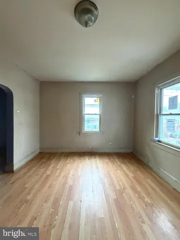 an empty room with wooden floor cabinet and windows